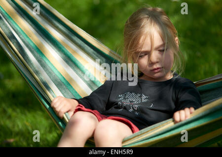 Portrait de petit enfant fille blonde allongé et se reposant dans un hamac, cour, jardin de l'été Banque D'Images