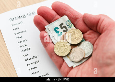 Une femme pauvre retraité senior une petite quantité d'argent comptant libre de faible valeur dans la main avec une liste de courses pour l'épicerie. England UK Banque D'Images