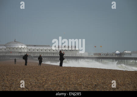 Les gens prennent des photos des grandes vagues, causés par une tempête, se briser sur la plage en face de la jetée de Brighton à Brighton, East Sussex, Angleterre. Banque D'Images