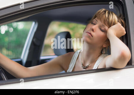 Jolie jeune femme blonde dormir dans une voiture Banque D'Images