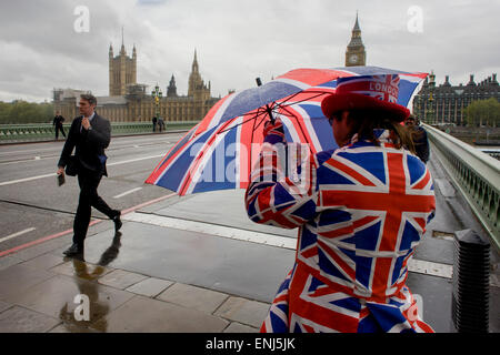 Des vents forts et les conditions météorologiques humides herald une semaine d'incertitude dans la Bretagne à moins de 24 heures avant l'élection générale. Peu probable que les perspectives d'un gouvernement majoritaire à la fin de la semaine, les offres d'orageuses entre les partis et le mécontentement des électeurs. Un dépliant touristique homme habillé en union jacks donne des détails d'un poisson et à proximité d'affaires à puce, en face du Palais de Westminster de Westminster Bridge. Banque D'Images