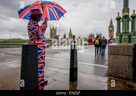 Des vents forts et les conditions météorologiques humides herald une semaine d'incertitude dans la Bretagne à moins de 24 heures avant l'élection générale. Peu probable que les perspectives d'un gouvernement majoritaire à la fin de la semaine, les offres d'orageuses entre les partis et le mécontentement des électeurs. Un dépliant touristique homme habillé en union jacks donne des détails d'un poisson et à proximité d'affaires à puce, en face du Palais de Westminster de Westminster Bridge. Banque D'Images