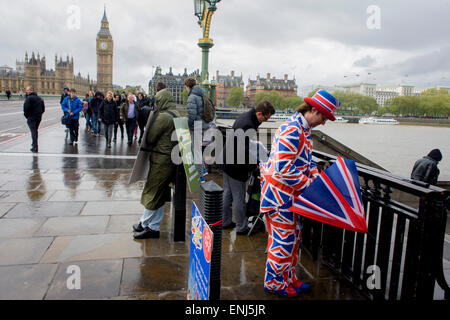 Des vents forts et les conditions météorologiques humides herald une semaine d'incertitude dans la Bretagne à moins de 24 heures avant l'élection générale. Peu probable que les perspectives d'un gouvernement majoritaire à la fin de la semaine, les offres d'orageuses entre les partis et le mécontentement des électeurs. Un dépliant touristique homme habillé en union jacks donne des détails d'un poisson et à proximité d'affaires à puce, en face du Palais de Westminster de Westminster Bridge. Banque D'Images