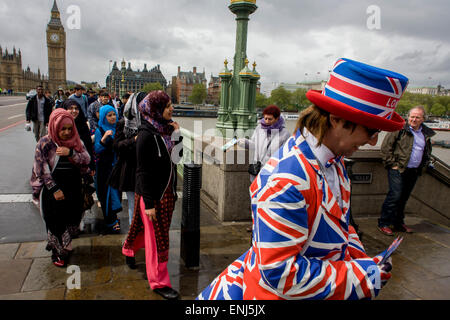Des vents forts et les conditions météorologiques humides herald une semaine d'incertitude dans la Bretagne à moins de 24 heures avant l'élection générale. Peu probable que les perspectives d'un gouvernement majoritaire à la fin de la semaine, les offres d'orageuses entre les partis et le mécontentement des électeurs. Un dépliant touristique homme habillé en union jacks donne des détails d'un poisson et à proximité d'affaires à puce, en face du Palais de Westminster de Westminster Bridge. Banque D'Images