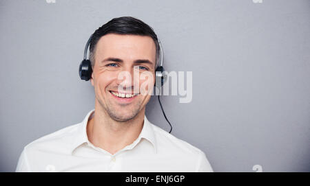 Portrait of a smiling male en assistant à la caméra sur le casque à fond gris Banque D'Images