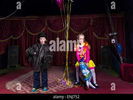 Jeune garçon habillé en clown debout sur scène avec fille en costume Holding dynamique ballon en forme de cheval Banque D'Images