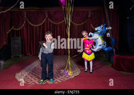 Jeune garçon habillé en clown debout sur scène avec fille en costume Holding dynamique ballon en forme de cheval Banque D'Images