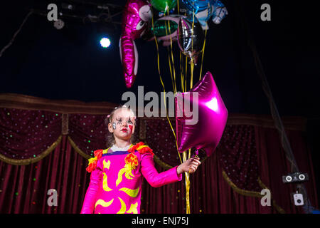 Fille mignonne avec visage peint et bright pink fantasy dress holding a bouquet de ballons colorés de gaz pendant une œuvre artistique performanc Banque D'Images