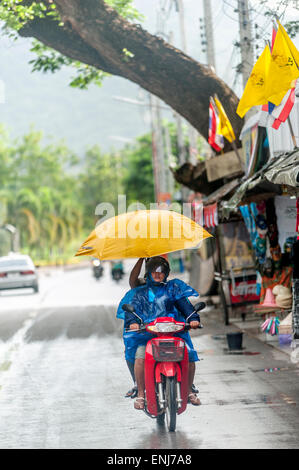 Couple avec un parapluie équitation une moto sous la pluie. Kanchanaburi, la province de Kanchanaburi, Thaïlande Banque D'Images