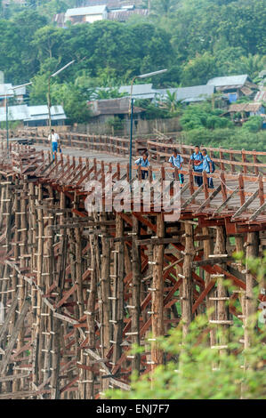 Les écoliers traversant le pont de bois branlant Saphan (Mon) Sangkhlaburi. La province de Kanchanaburi. La Thaïlande. Banque D'Images