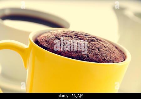 Libre d'un mug cake au chocolat dans une tasse de porcelaine jaune et une tasse de café Banque D'Images