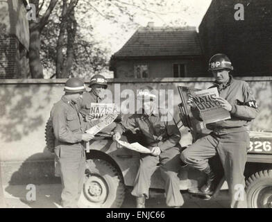 Lisez à propos de policiers militaires américains la reddition de l'Allemagne dans le journal Stars and Stripes. 1945 Banque D'Images