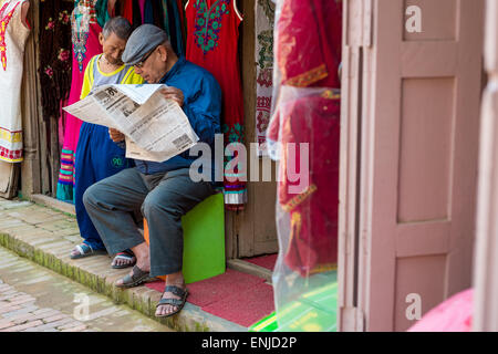 Deux hommes la lecture de l'actualité dans Bhaktapur, Népal Banque D'Images