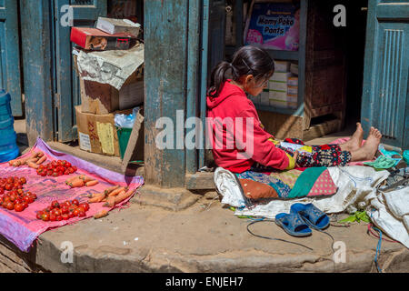 Bhaktapur, 20 mars 2015 - une jeune fille népalaise est la lecture d'un magazine tout en restant assis sur le sol Banque D'Images