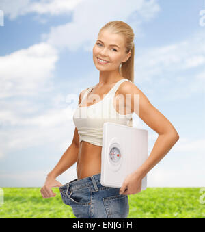 Smiling woman showing grand pantalon et échelles holding Banque D'Images