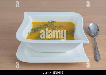 Soupe de carottes fait maison avec de la coriandre dans un bol en forme de carré blanc Banque D'Images