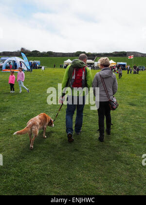 Un homme et une femme marcher leur chien dans un champ Banque D'Images