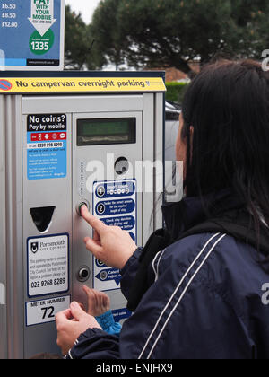 Une dame à l'aide d'une machine de stationnement Payez et affichez Banque D'Images