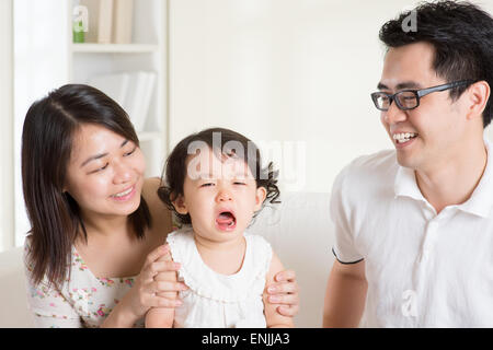 Les parents est réconfortant leur fille pleurer. La famille asiatique à la maison. Banque D'Images