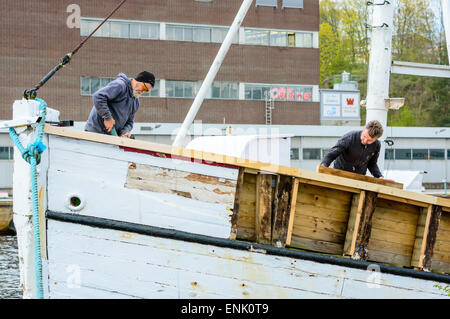 KARLSHAMN, Suède - mai 06, 2015 : deux travailleurs inconnus rénover un vieux bateau de pêche dans le port de Douarnenez. Personnes travaillent dur et bateau, c'est dépouillé de bois. Banque D'Images