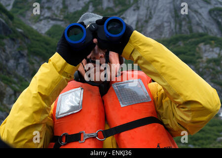 Avec des jumelles de voyageurs sur bateau de croisière safari s'efforcer à l'ancre à gués la terreur, Endicott Arm, la Forêt Nationale Tongass, juin Banque D'Images