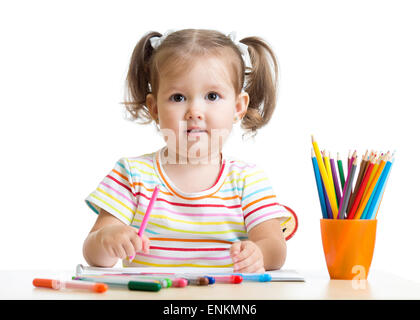 La petite fille dessine avec des crayons sitting at table Banque D'Images