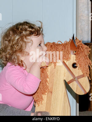 A 10 mois bébé fille de race blanche de ses promenades à cheval à bascule en bois. Banque D'Images