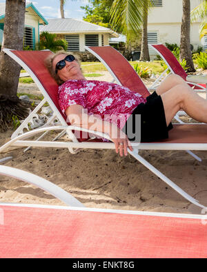 A senior woman bénéficie d'couché dans une chaise de plage dans un lieu de villégiature dans les Caraïbes. Sainte Croix, Îles Vierges des États-Unis. Banque D'Images