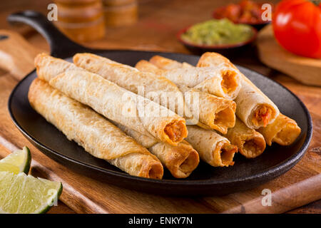 Un plat de poulet délicieux taquitos avec salsa, guacamole, et de la chaux. Banque D'Images