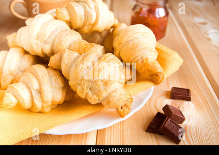 Des croissants frais fait maison avec de la confiture (confiture) et de chocolat sur serviette et table en bois Banque D'Images