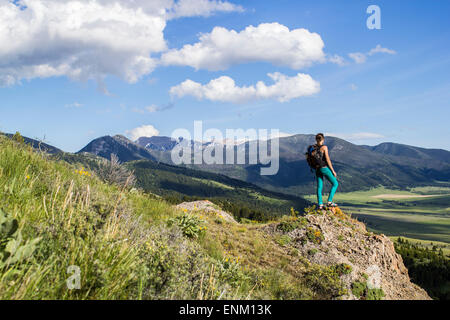 Femme se dresse sur un rocher à la recherche dans les Montagnes Rocheuses du Montana Banque D'Images