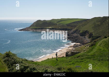 Couple en train de marcher sur le gazon couvert chemin falaise à l'abri de la baie de l'automne au-dessus de la mer scintillante bleu avec pointe et de champs. Banque D'Images