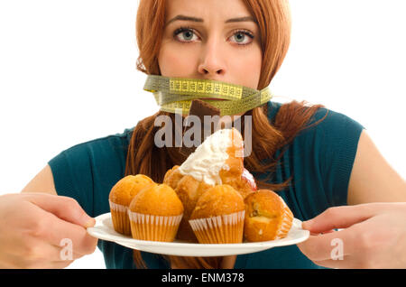 Femme d'un centimètre sur sa bouche, incapable de manger tous les bonbons et le sucre, beaucoup de témoins sur une assiette. Suivre un régime sans bonbons Banque D'Images