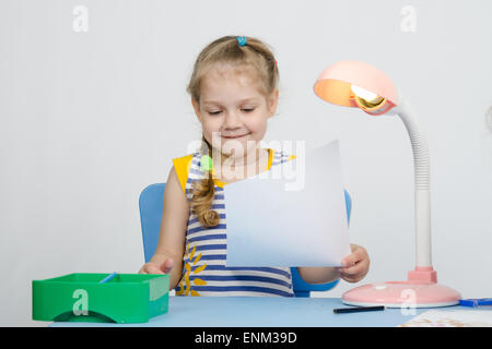 Fille de quatre ans attire les Européens crayon sur une feuille, assis à la table Banque D'Images