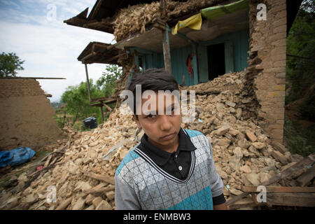 Un garçon se tient devant sa maison effondrée dans Karvre District, le Népal après le tremblement de terre de 2015. Banque D'Images