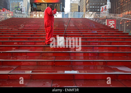 Nettoyage du travailleur rouge iconique pas derrière le kiosque TKTS discount theatre tickets à Midtown Manhattan, NYC Banque D'Images