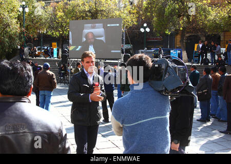 La Paz, Bolivie, le 8 mai 2015. Journaliste chilienne Amaro Gómez-Pablos les rapports pour la TVN Chili (Televisión Nacional de Chile) news channel de La Paz en Bolivie's présentation finale à la Cour internationale de Justice de La Haye est transmis en direct sur un écran géant dans la région de Plaza Murillo. Les premières audiences de la Bolivie en cas récupérer l'accès à l'océan Pacifique contre le Chili ont eu lieu dans la CIJ cette semaine, les audiences ont été de débattre de l'opposition chilienne que la cour n'a pas la compétence pour juger l'affaire. Credit : James Brunker / Alamy Live News Banque D'Images