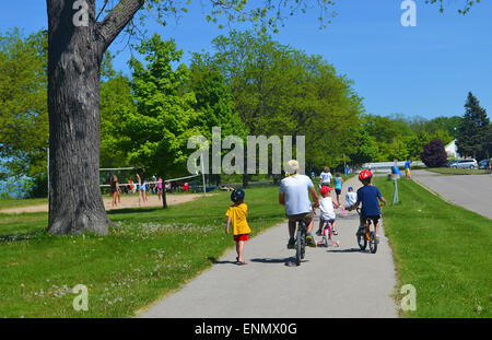 Une famille et petits enfants sur des vélos dans un parc au printemps. Banque D'Images