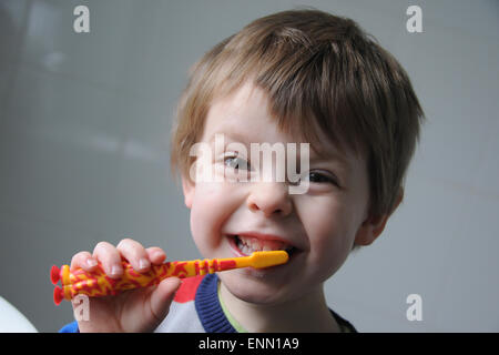 Un garçon de trois ans qui nettoyer les dents avec une brosse à dents. Banque D'Images