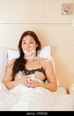 Woman drinking coffee in bed à summercottage dans Laugar en Islande du nord Banque D'Images