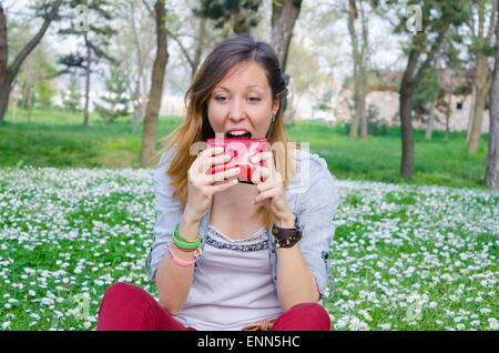 Brunette a éclaté au printemps en essayant de manger son portefeuille parmi les marguerites Banque D'Images