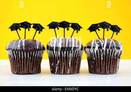 Heureux le jour de Graduation party petits gâteaux au chocolat avec graduation cap hat topper décorations, en jaune, noir et blanc thème de partie Banque D'Images