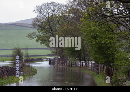 Skipton, Yorkshire du Nord, au Royaume-Uni. 9e mai 2015. Routes de campagne et les champs des agriculteurs sont couverts dans l'eau le long de la vallée de l'Aire, près de Skipton, Yorkshire du Nord. La rivière Aire éclate ses banques après les fortes pluies de la nuit entraîner jusqu'à 2 pieds de l'eau pour couvrir la terre environnante. Crédit : Tom Holmes / Alamy Live News. Banque D'Images