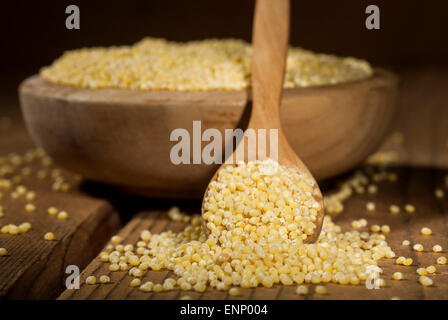 Millet dans un bol en bois et une cuillère sur un fond de bois. Banque D'Images