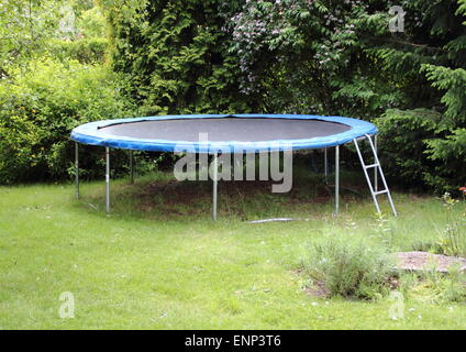 Trampoline bleu sur la pelouse au jardin Banque D'Images