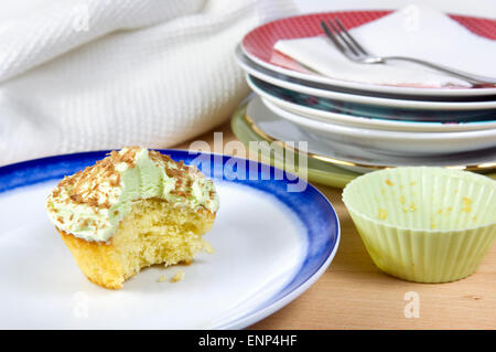 Cupcake pistache avec des copeaux de chocolat, glaçage vert et une collation prise hors de, sur une plaque bleu et blanc Banque D'Images