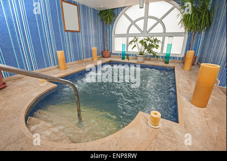 Grande piscine jacuzzi dans la salle de spa luxueux, avec des bougies centre Banque D'Images