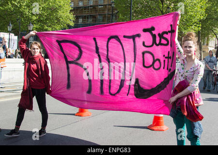 Londres, 9 mai 2015. Deux femmes occupent un bandeau rose avec les mots 'Riot just do it" et une parodie de la marque Nike 'swoosh' mars lors d'une manifestation dans le centre de Londres pour protester contre le 7 mai 2015 résultats de l'élection générale, qui a vu les conservateurs remporter une majorité. Credit : Patricia Phillips/Alamy Live News Banque D'Images