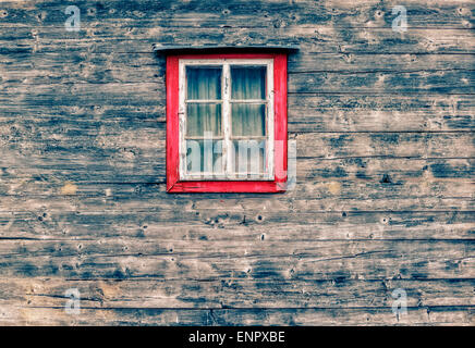 Façade en bois d'une cabane de montagne, avec une vieille fenêtre et des rideaux dans le centre de la photo Banque D'Images
