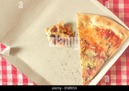 Pizza Slice et Fast Food les restes dans la boîte de carton sur la table de cuisine, style retro droit tonique, Selective Focus Banque D'Images